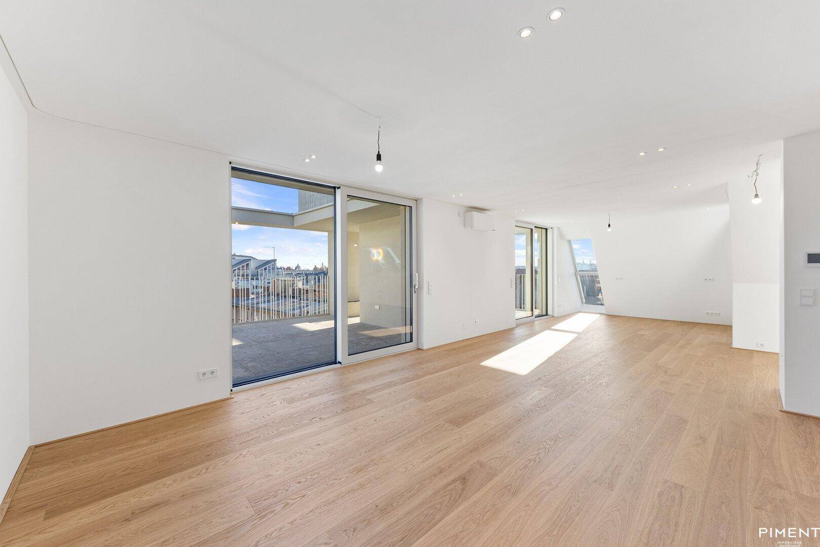 Heller, geräumiger Wohnbereich mit Holzboden und Zugang zu einer großen Terrasse.