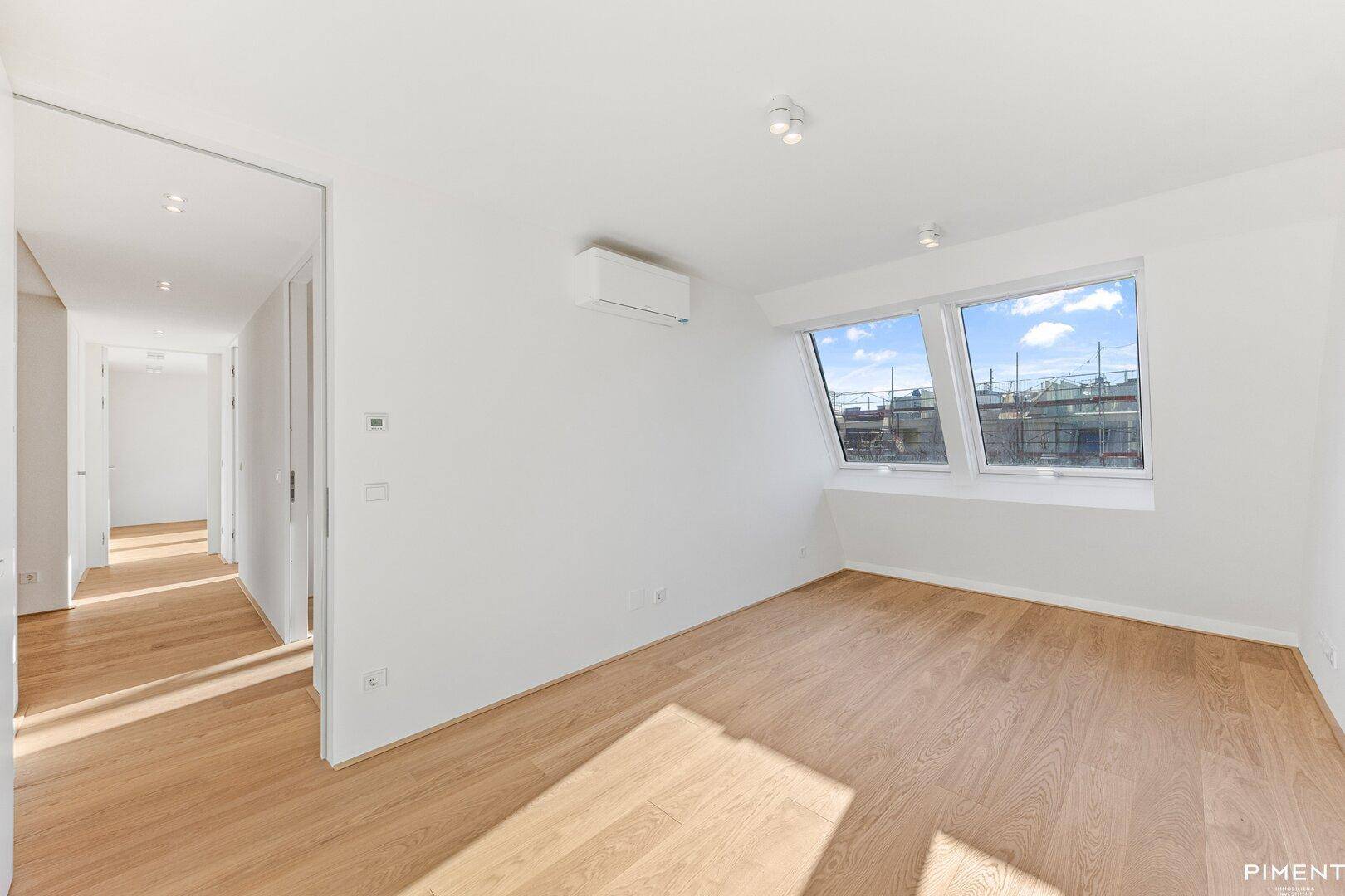 Helles Zimmer mit Holzboden, Dachfenstern und Klimaanlage, ideal als Schlaf- oder Arbeitszimmer.