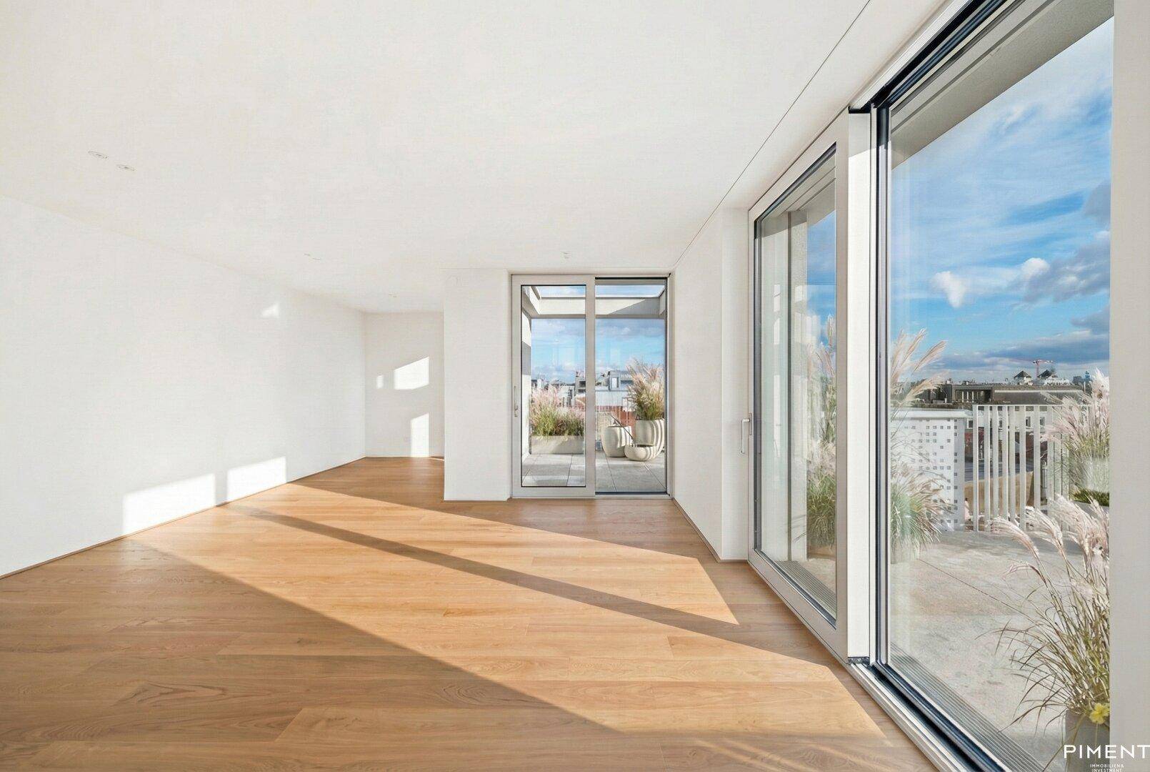 Heller, leerer Raum mit Holzboden und großen Schiebetüren zur sonnigen Terrasse.