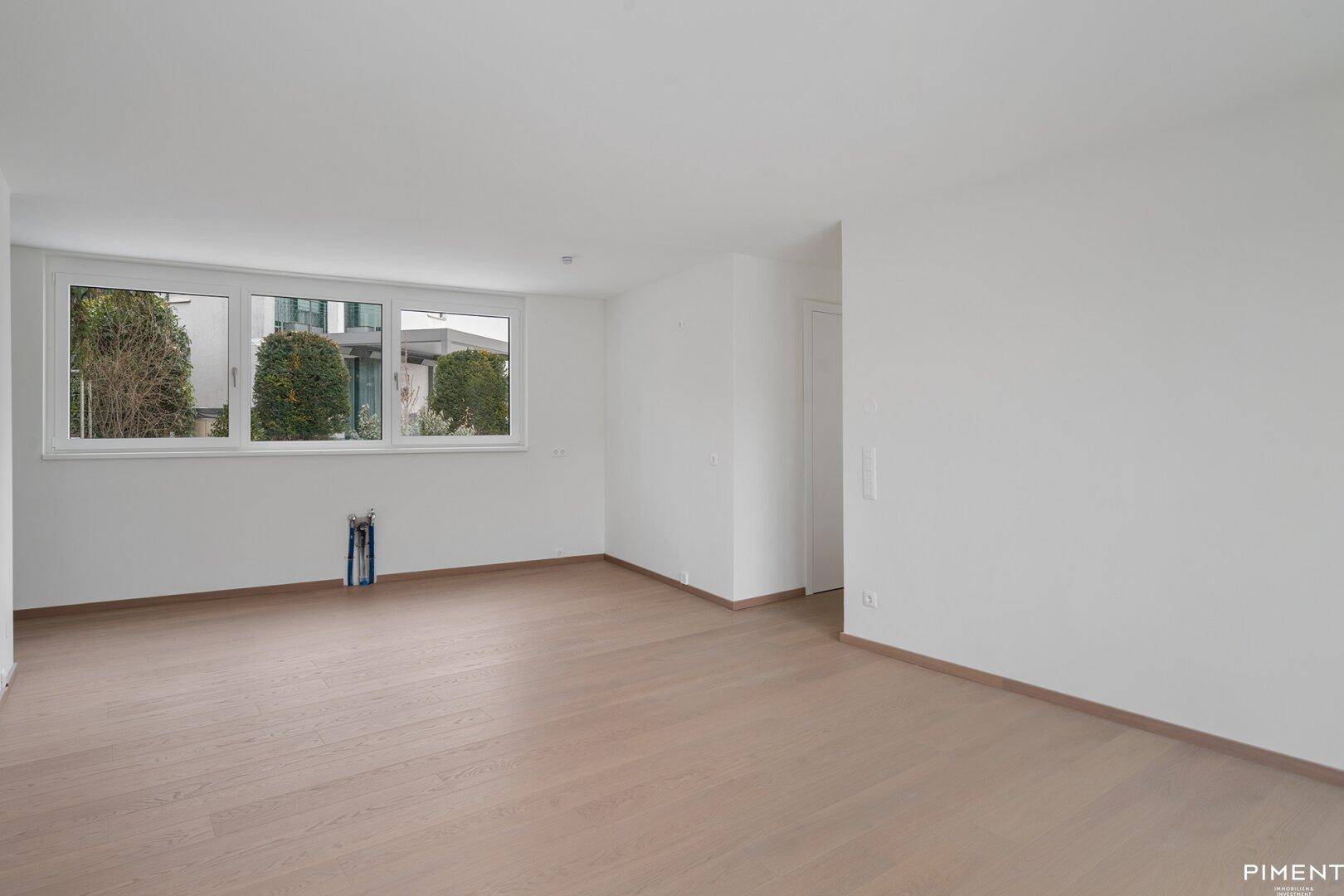 Leerer Küchenbereich mit Anschlüssen für Geräte und großen Fenstern, bereit zum Einbau.