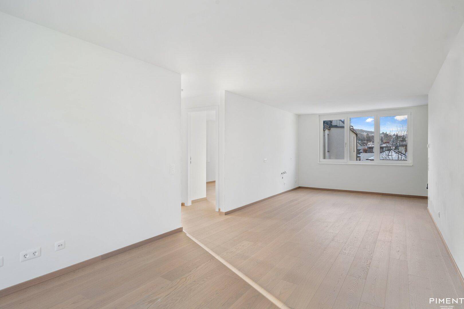 Heller und offener Raum mit Holzboden und einem Fenster, das viel Tageslicht hereinlässt.