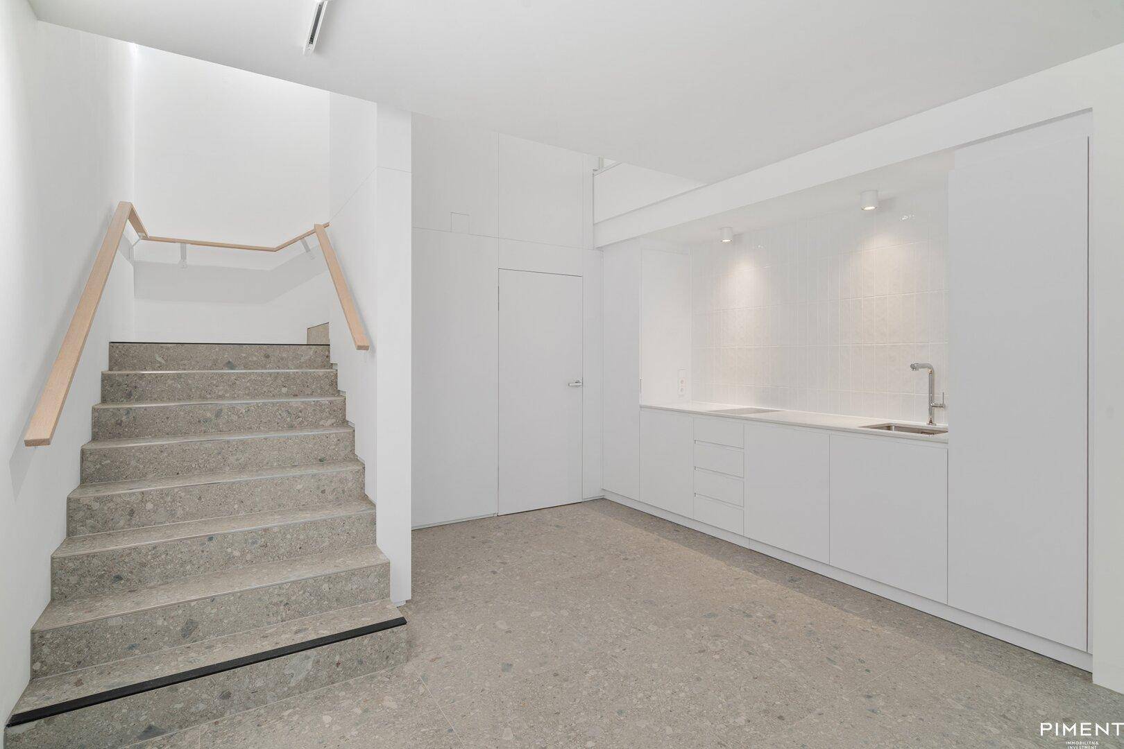 Treppenaufgang und eine integrierte, moderne Küchenzeile in weißem Design.