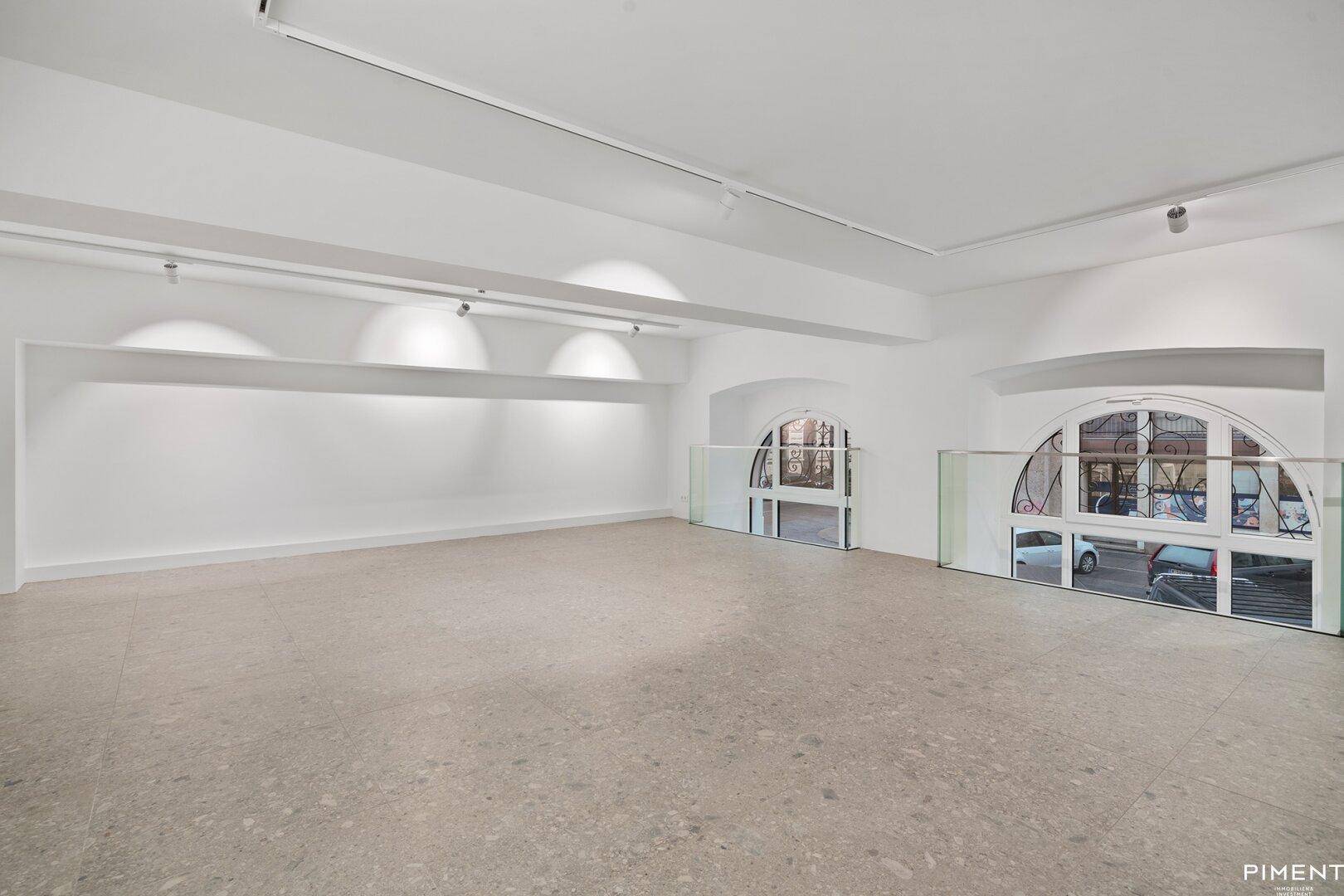 Innenansicht des Gewerberaums mit markanten Rundbogenfenstern und Blick zur Straße.