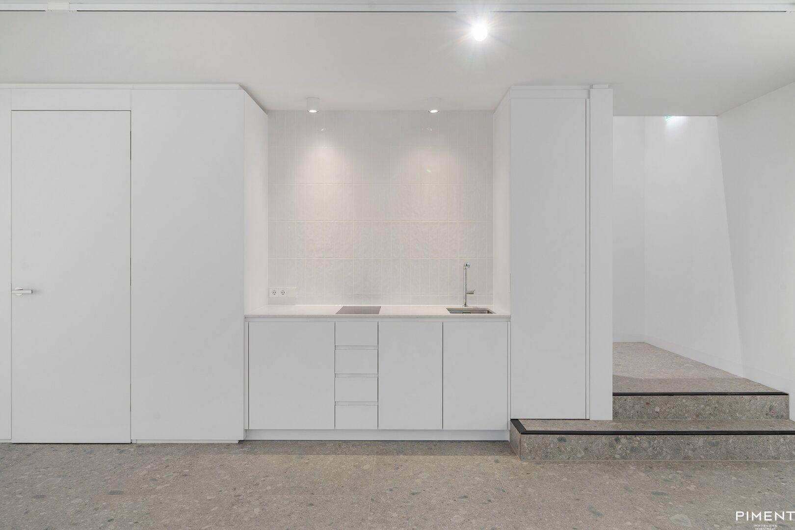 Moderne, minimalistische Küchenzeile mit Induktionskochfeld und Spüle in weißem Design.