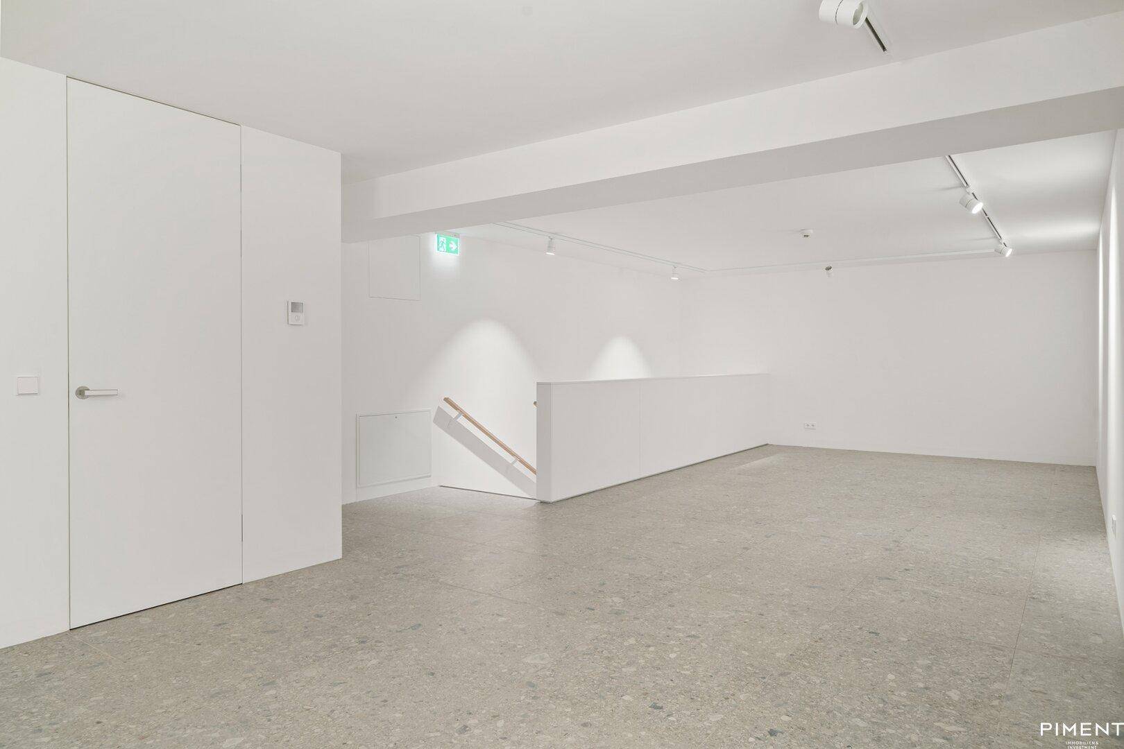 Heller Gewerberaum mit Treppenaufgang, hohen Decken und integrierten Schränken.