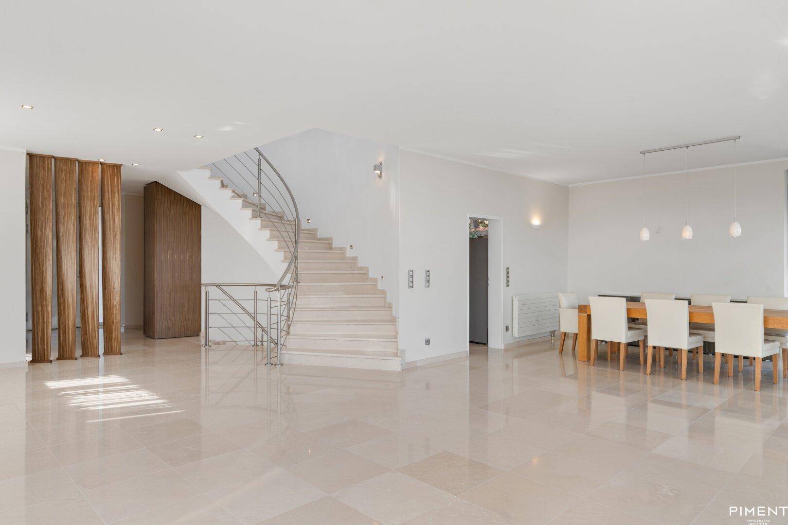 Großzügiger offener Bereich mit elegantem Essplatz und einer modernen Treppe, die die Etagen verbindet.