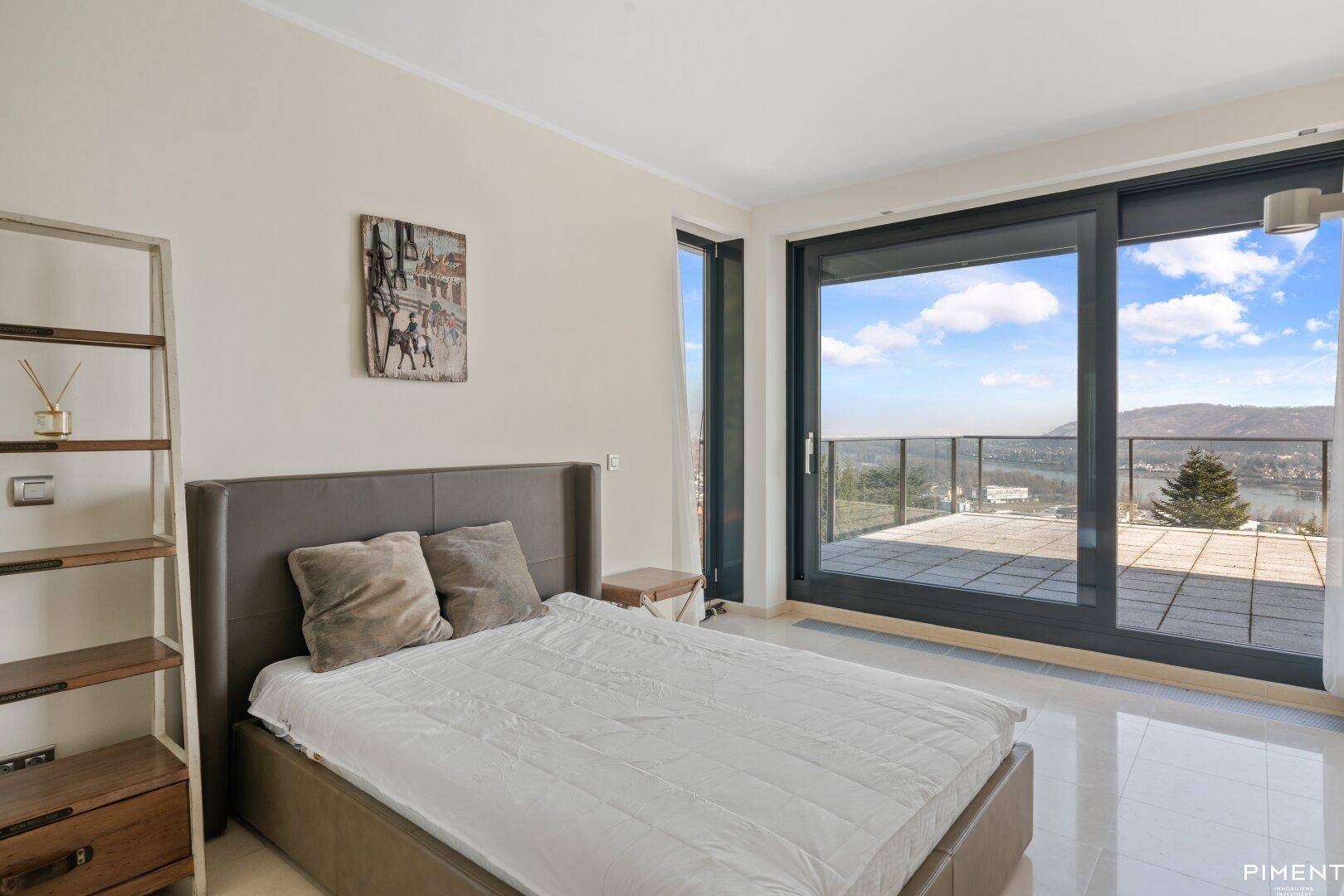 Gemütliches Schlafzimmer mit Bett und direktem Zugang zu einer Terrasse mit malerischem Blick auf den Fluss.