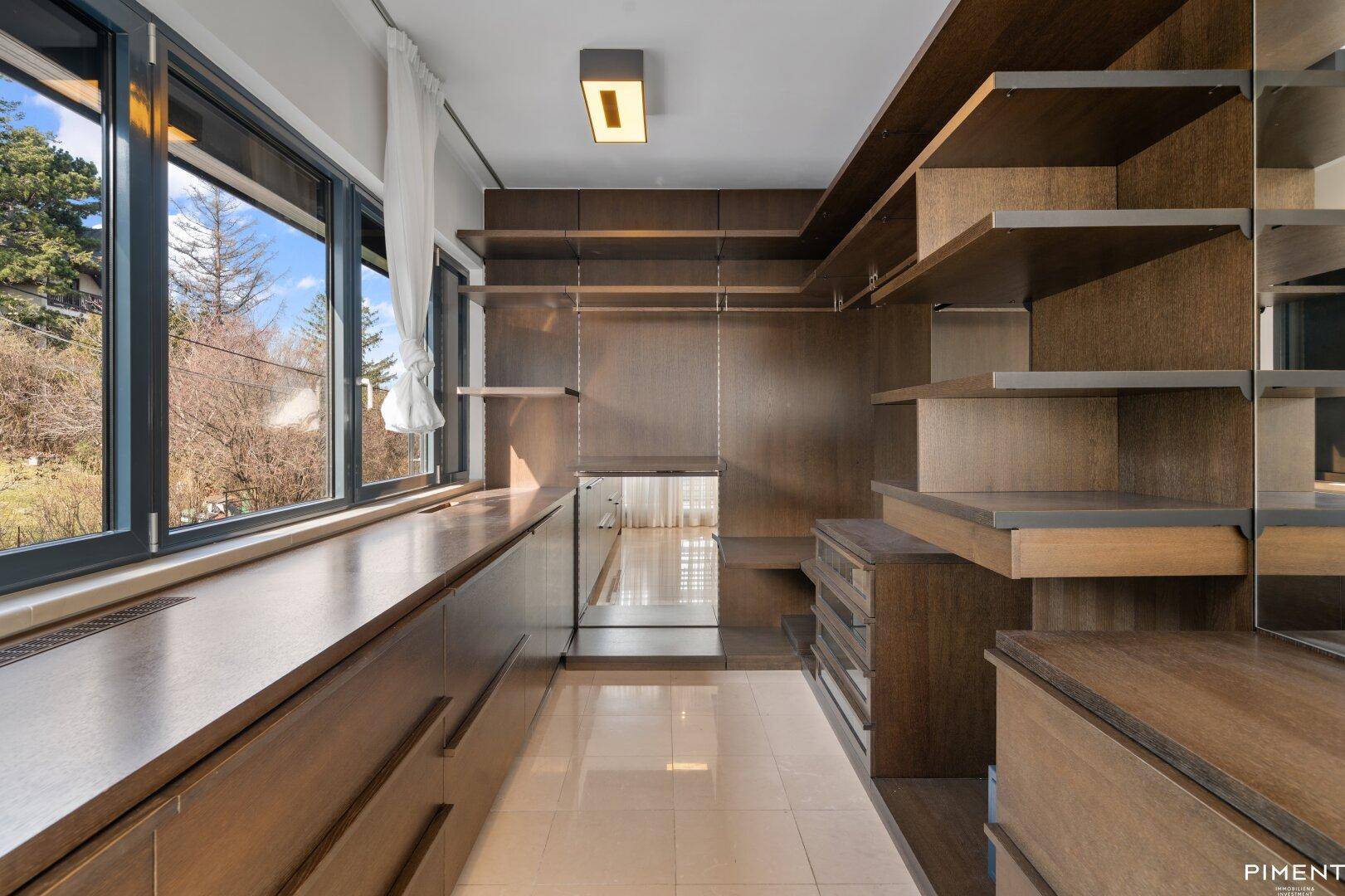 Geräumiger begehbarer Kleiderschrank mit maßgefertigten Holzregalen und viel Stauraum.