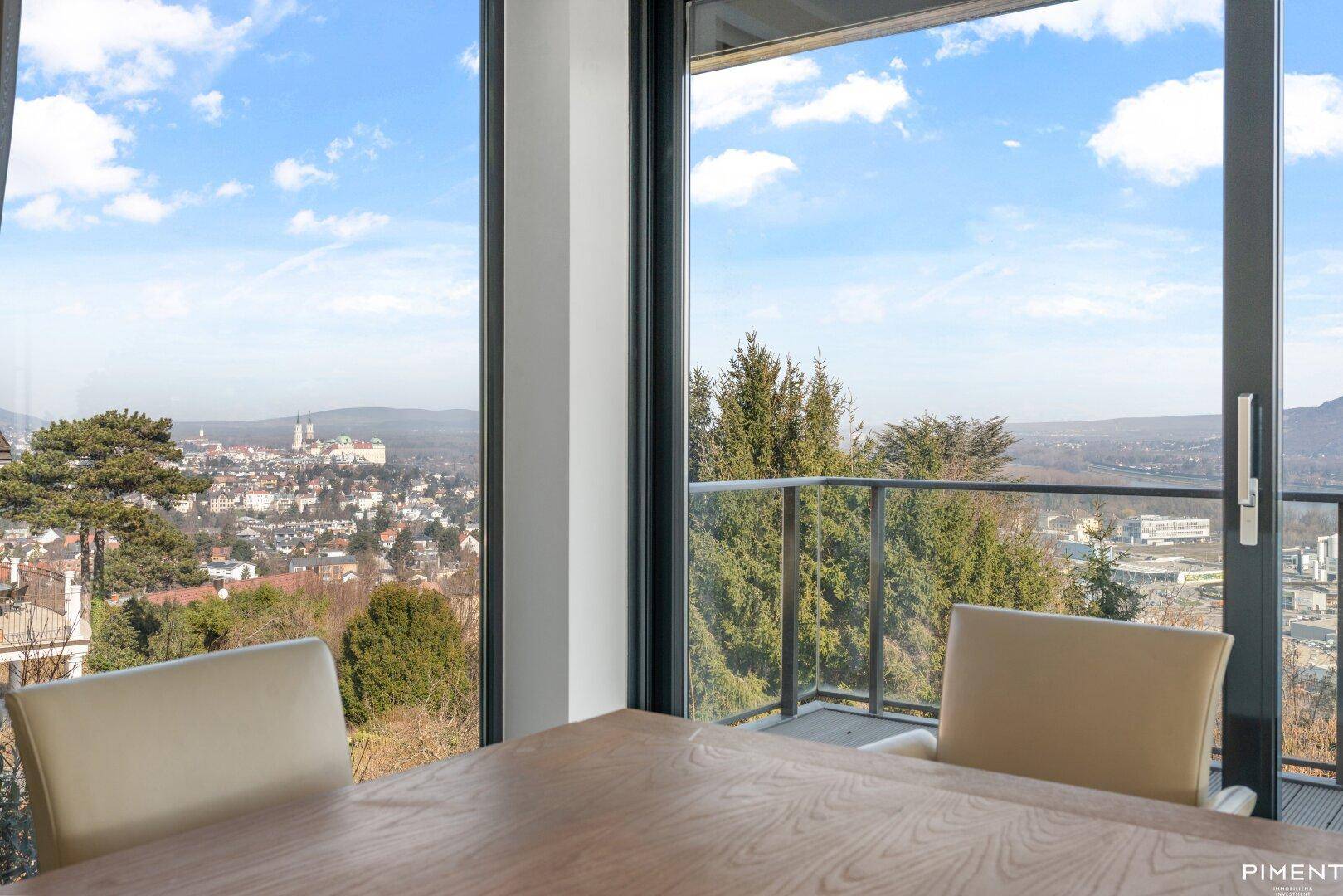 Essbereich mit Holztisch und Stühlen, bietet durch die großen Fenster einen malerischen Blick auf die Stadt.