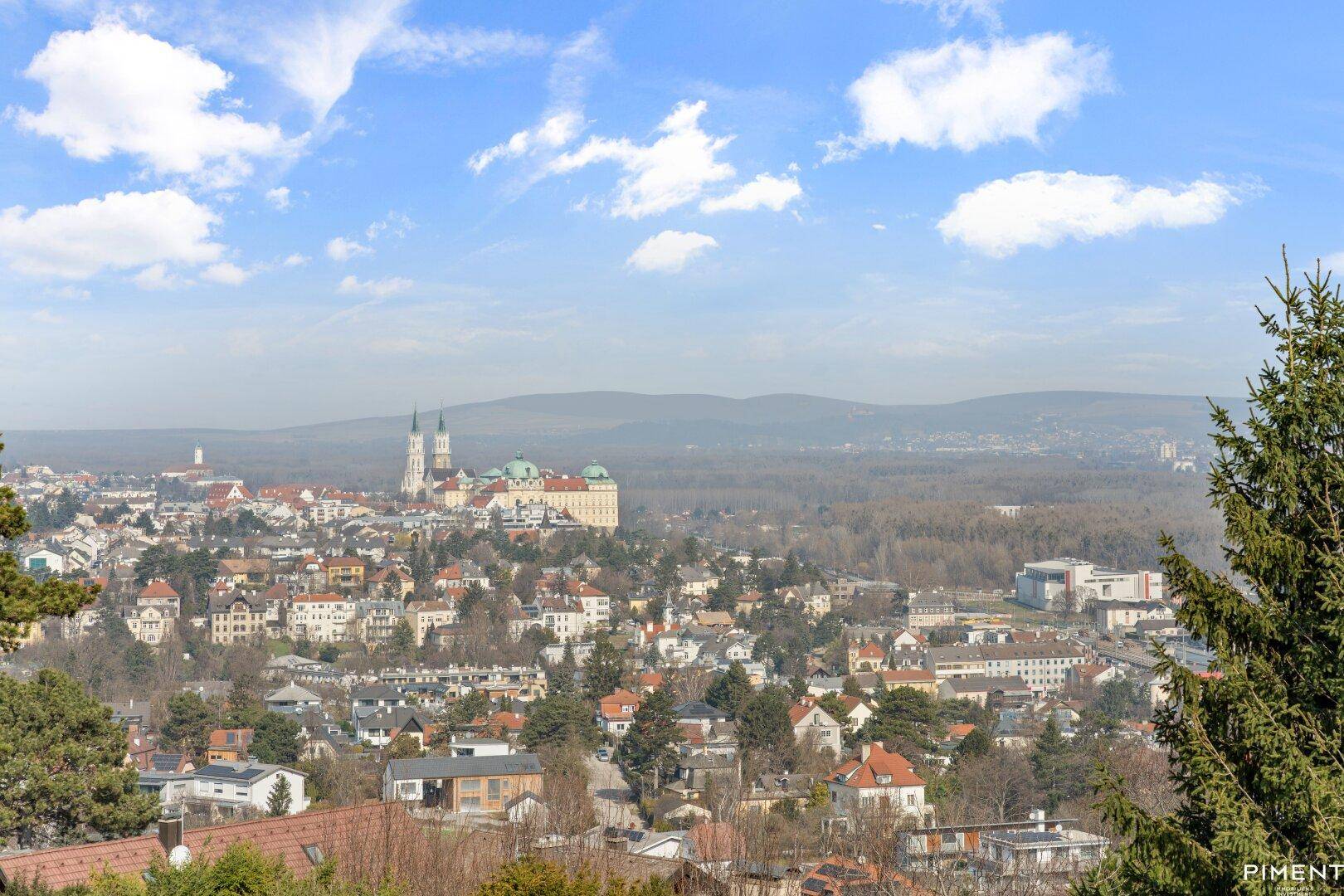 Panoramablick auf eine historische Stadt mit ihren Gebäuden, eingebettet in eine hügelige Landschaft.