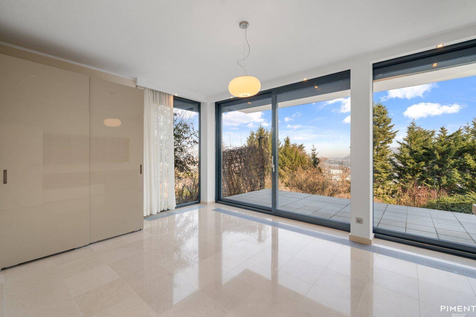 Helles Schlafzimmer mit Fliesenboden und großen Schiebetüren, die zu einer Terrasse mit Weitblick führen.
