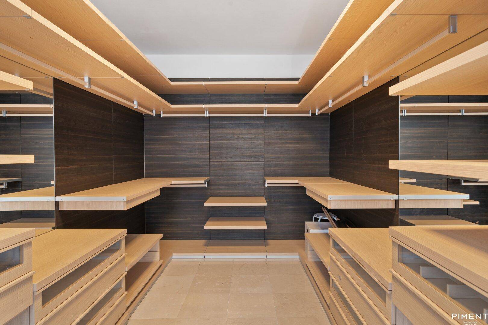 Moderner begehbarer Kleiderschrank mit eleganten Holzregalen und integrierten Schubladen für optimale Organisation.