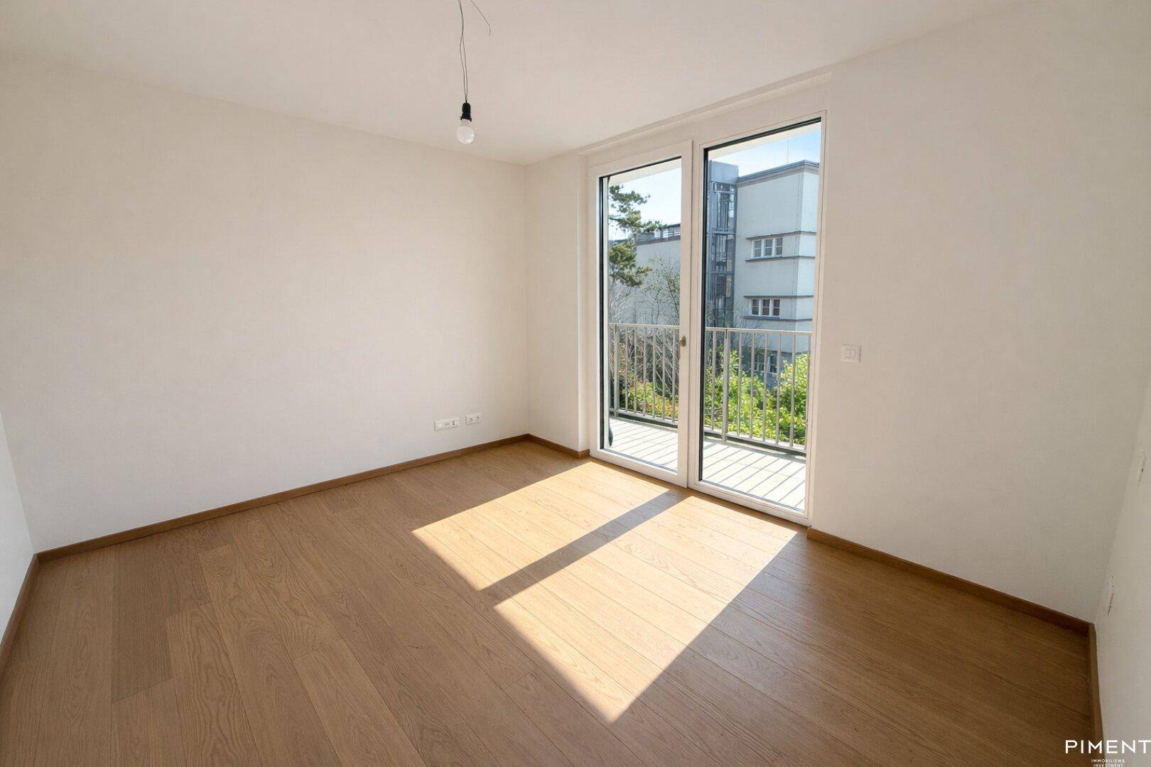 Helles Zimmer mit Parkettboden und Zugang zu einem französischen Balkon, ideal als Schlafzimmer.