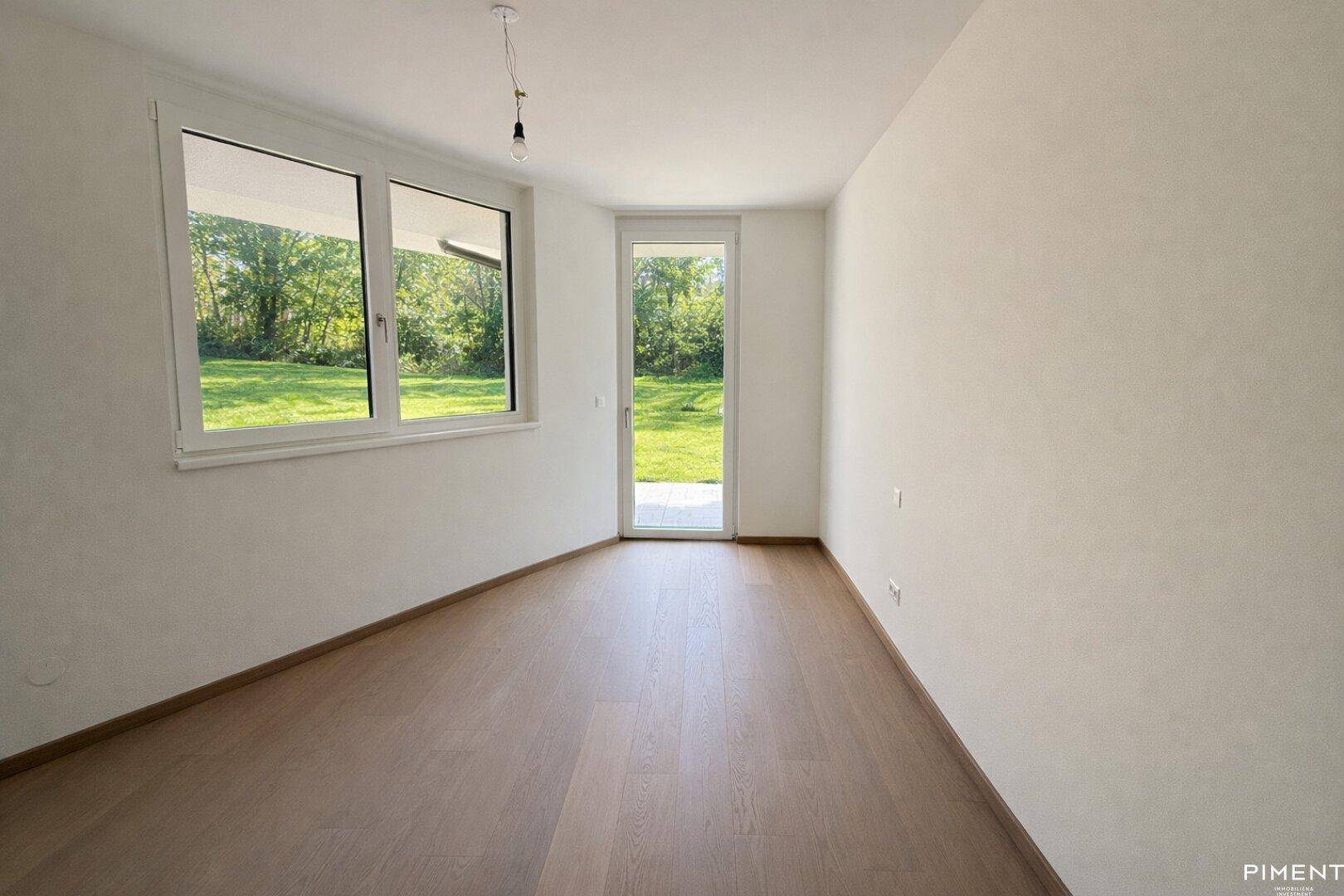 Helles Zimmer mit Holzboden, Fenster und Glastür zum Gartenbereich, ideal als Schlaf- oder Gästezimmer.