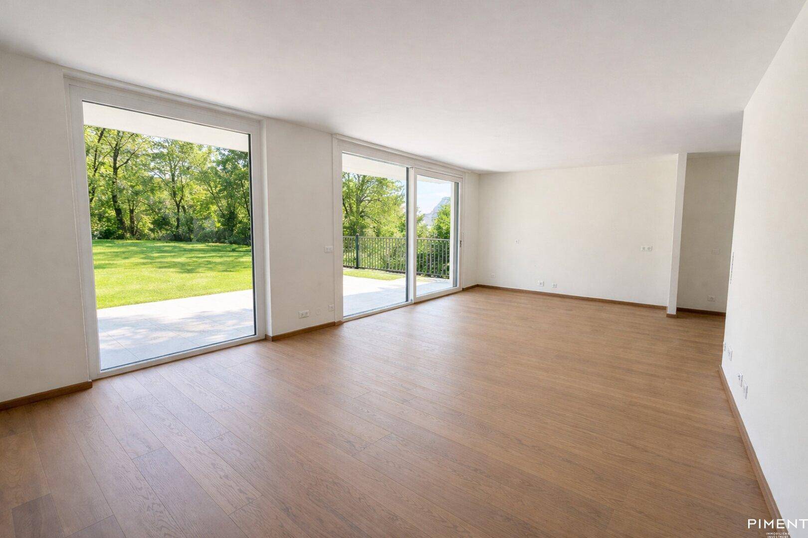 Geräumiges Wohnzimmer mit Eichenparkett, großen Fensterfronten und direktem Zugang zur Terrasse.