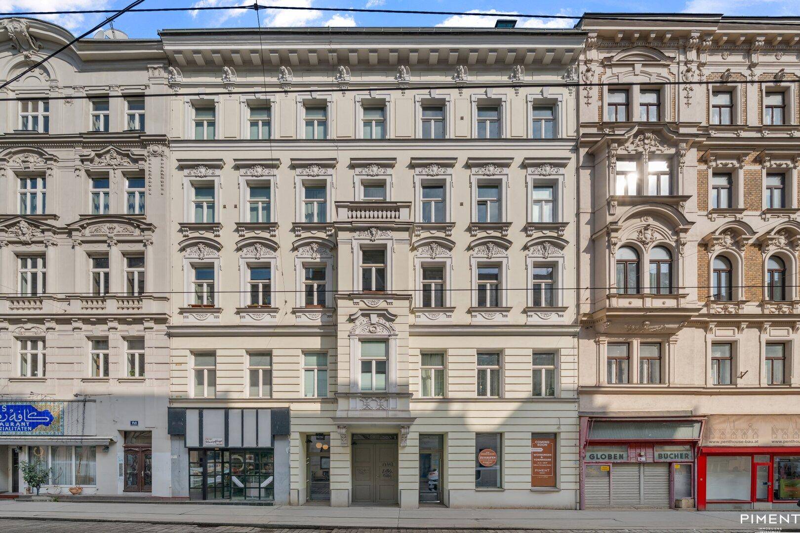 Historisches Gebäude mit reich verzierter Fassade, kleinen Balkonen und klassischer Architektur in urbaner Umgebung.