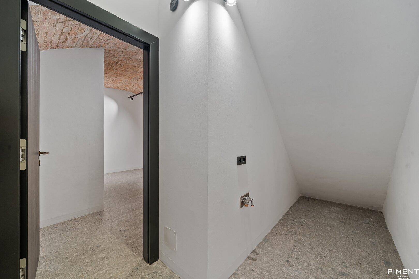 Abstellraum mit schräger Decke, Steinboden und Anschlussmöglichkeiten.
