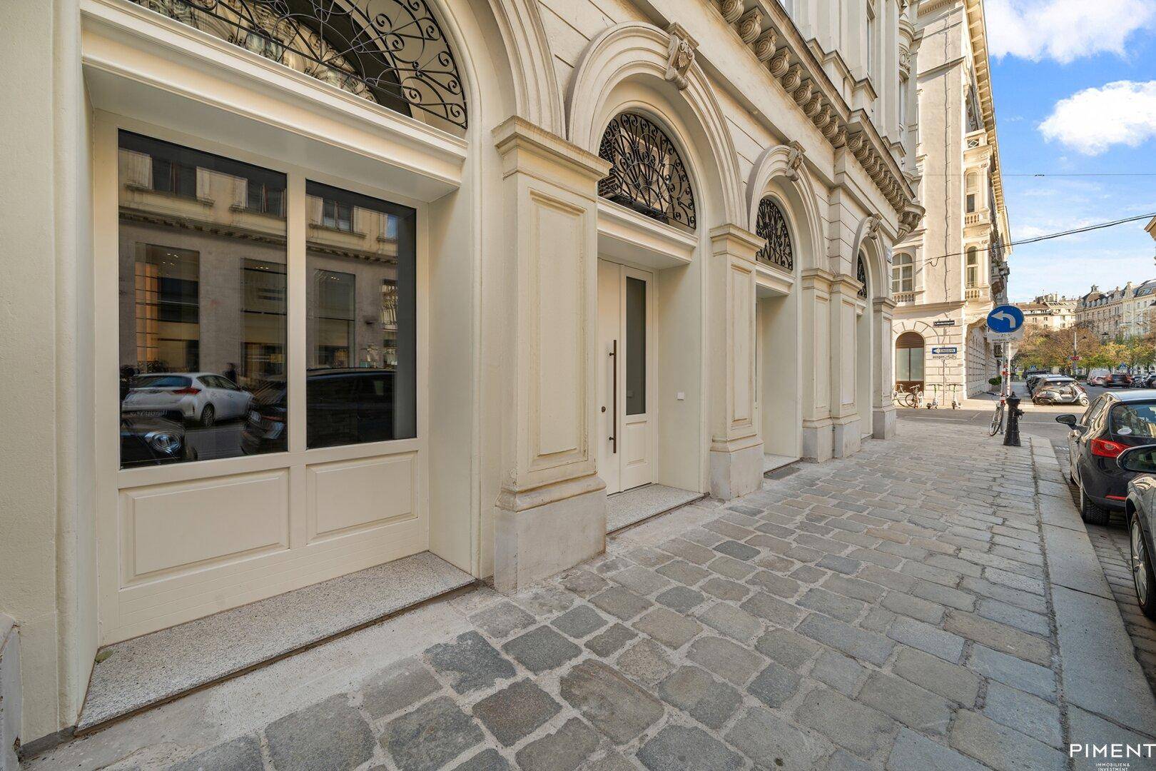 Historische Fassade eines Gebäudes mit großen Bogenfenstern und Kopfsteinpflaster.
