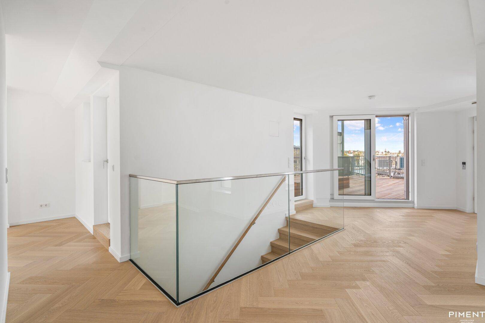 Heller Flurbereich mit moderner Treppe, Glasgeländer und Zugang zu weiteren Räumen.