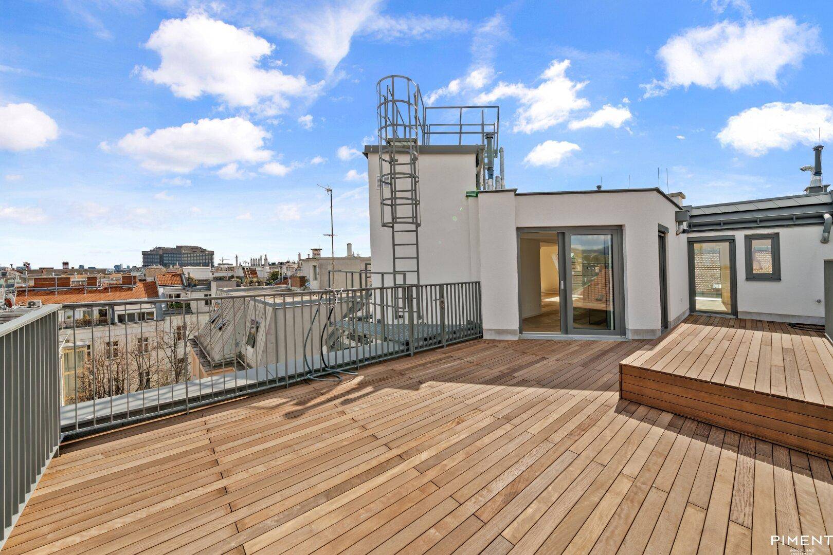 Geräumige Dachterrasse mit Holzboden und Zugang zu den Innenräumen des Penthouses.