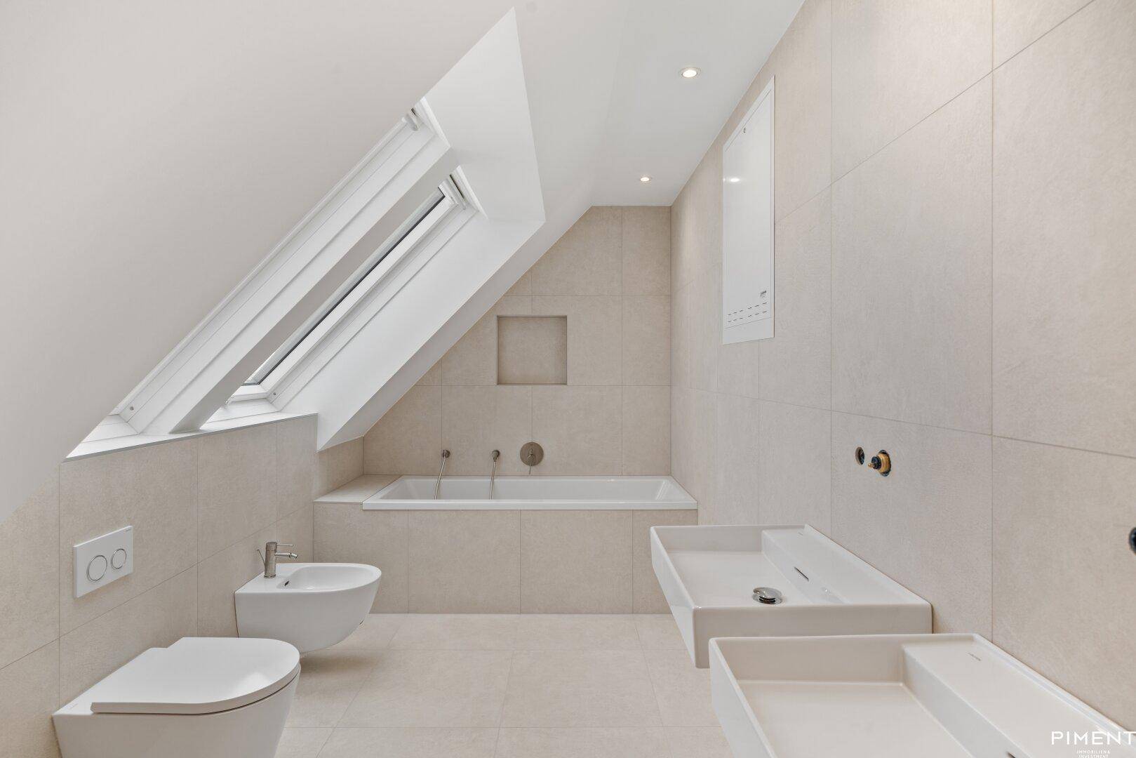 Modernes Badezimmer mit Badewanne, Bidet, Wand-WC und Dachfenster.