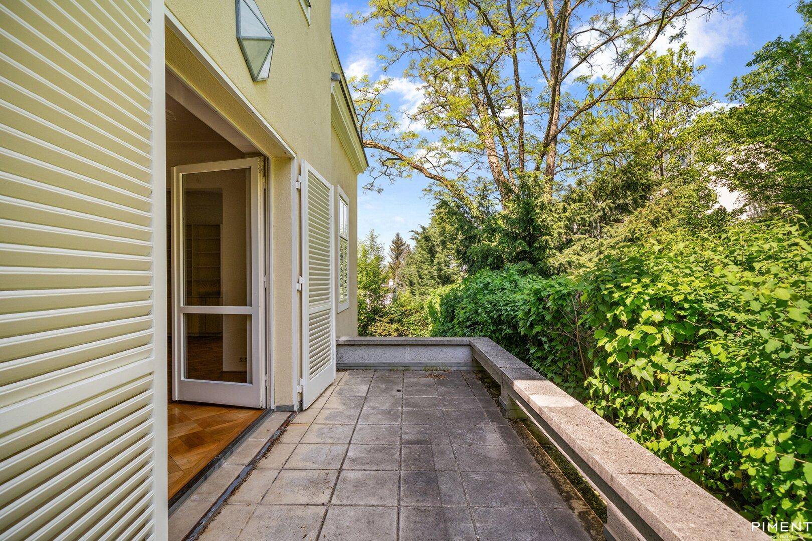 Kleiner Balkon mit Steinplatten und Blick auf üppiges Grün.
