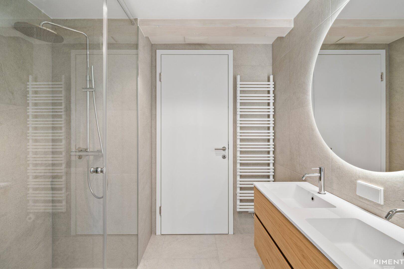 Modernes Badezimmer mit begehbarer Dusche, Einzelwaschbecken und beheiztem Handtuchhalter.