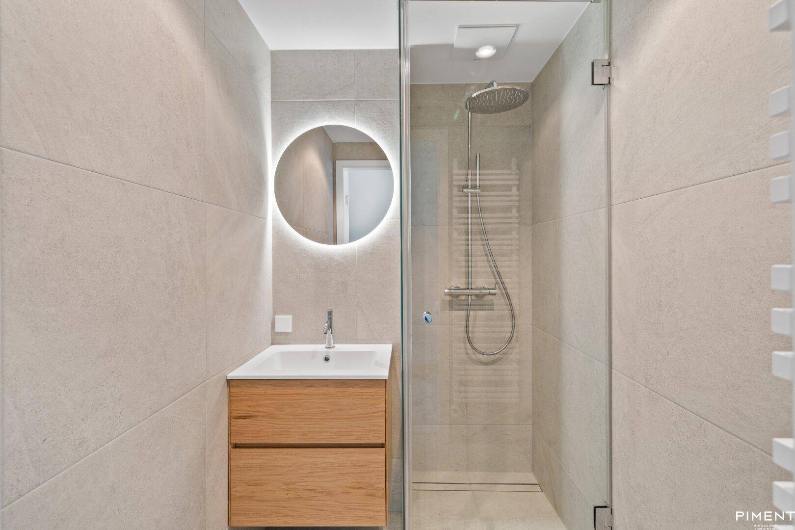 Elegantes Badezimmer mit begehbarer Dusche, Holzwaschtisch und beheiztem Handtuchhalter.