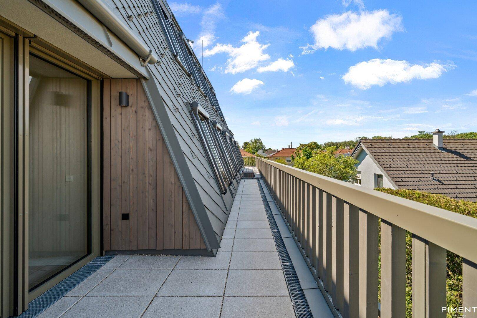 Langer Balkon entlang der Fassade mit Holzelementen und weitem Ausblick.