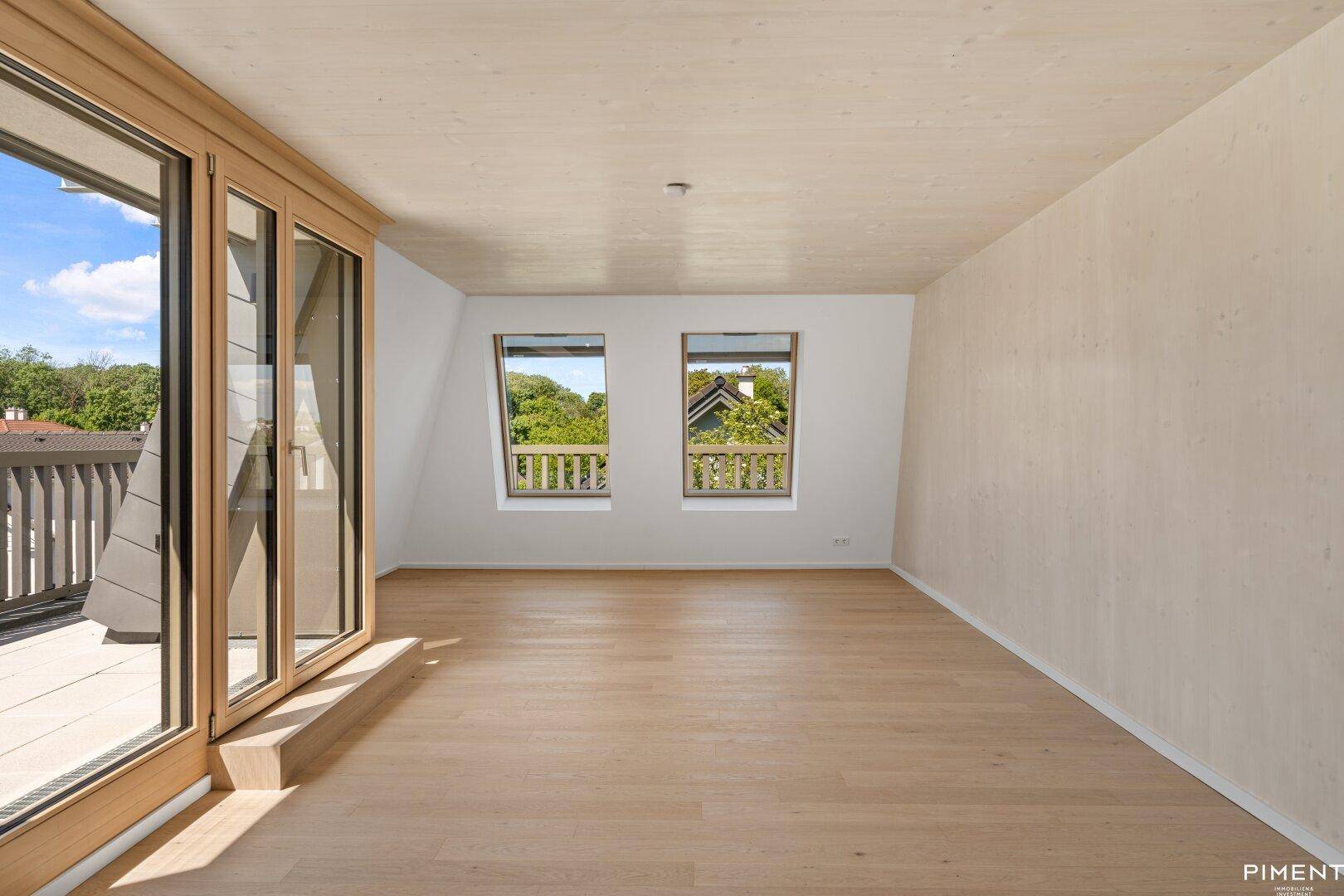 Geräumiges Zimmer mit hellem Holzboden und Zugang zu einem Außenbereich mit schöner Aussicht.