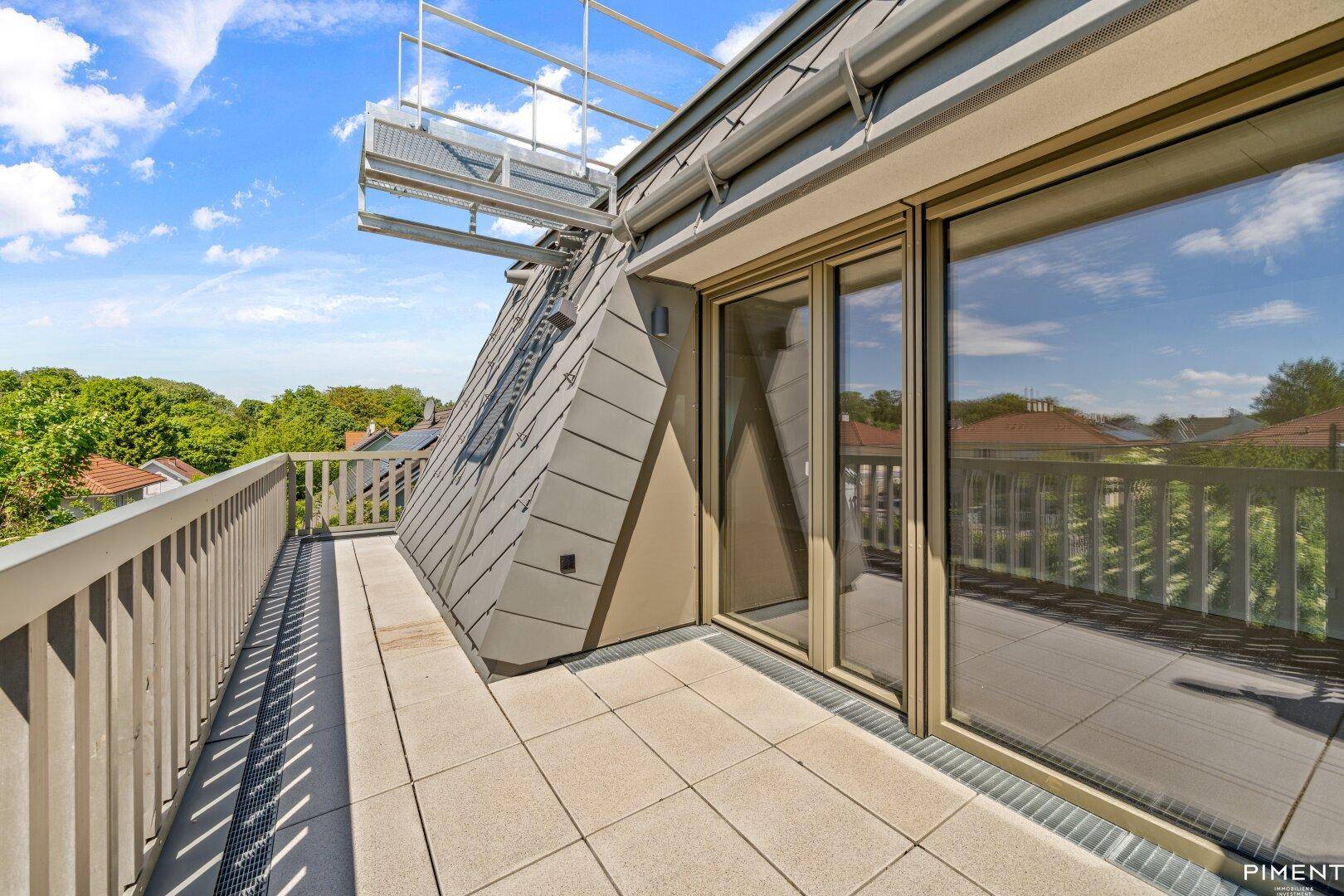 Große Dachterrasse mit Fliesenboden und weitem Blick über die Baumwipfel und Dächer.