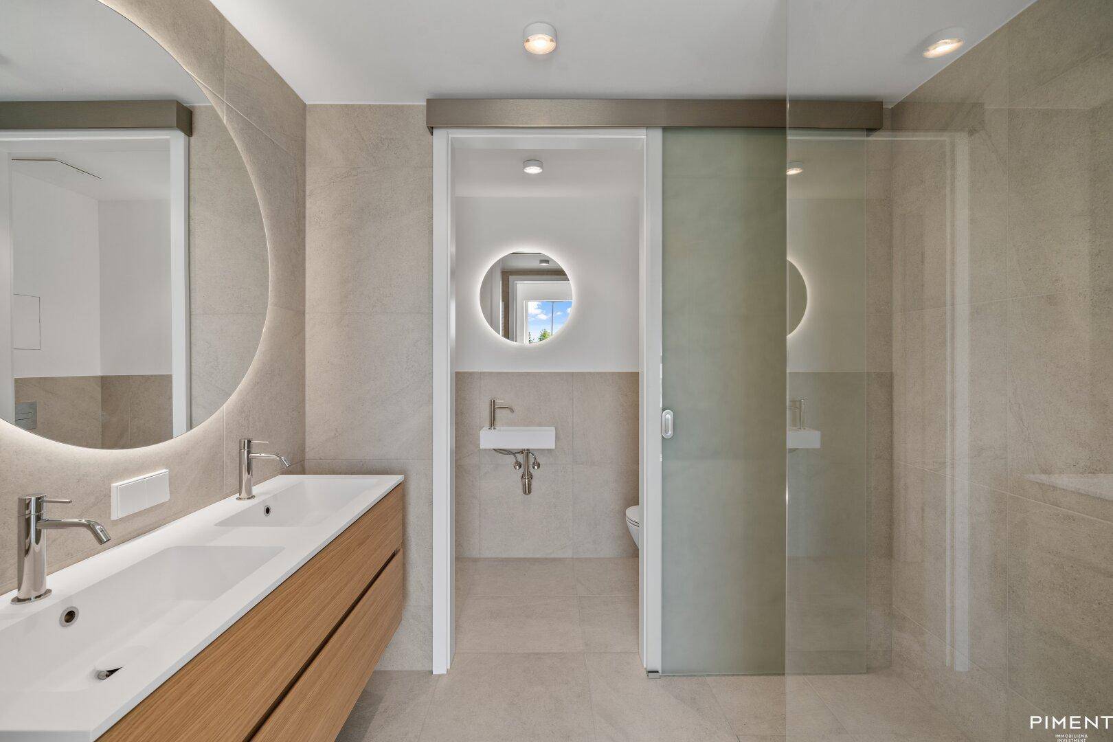 Modernes Badezimmer mit Doppelwaschbecken, großem Spiegel und separatem Duschbereich.