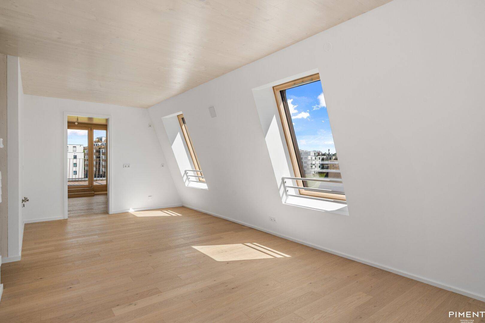 Geräumiger Wohnbereich mit Holzboden und schrägen Dachfenstern für viel Licht.