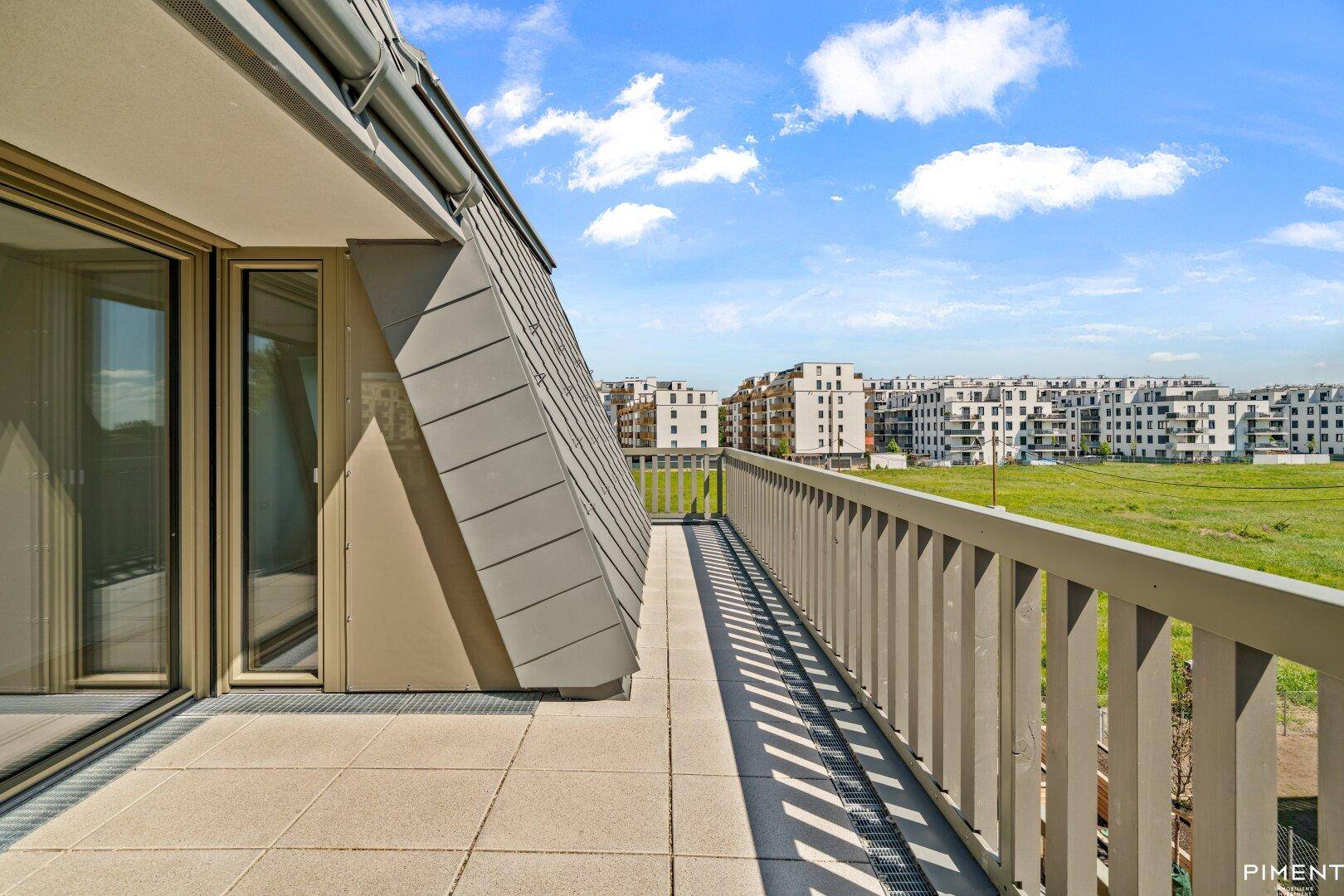 Weitläufige Terrasse mit weitem Blick über grüne Felder und die umliegende Wohnbebauung.