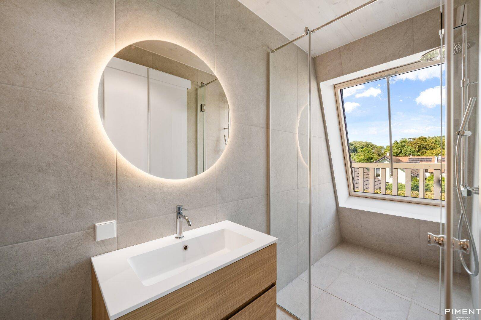Modernes Badezimmer mit begehbarer Dusche, beleuchtetem Spiegel und Dachfenster.