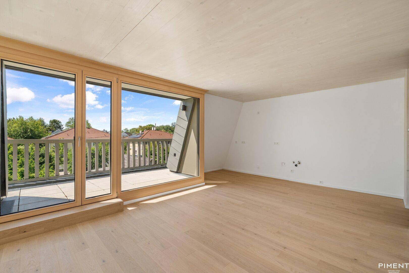 Helles Zimmer mit Holzboden und Zugang zu einer großen Terrasse, ideal für flexible Nutzung.
