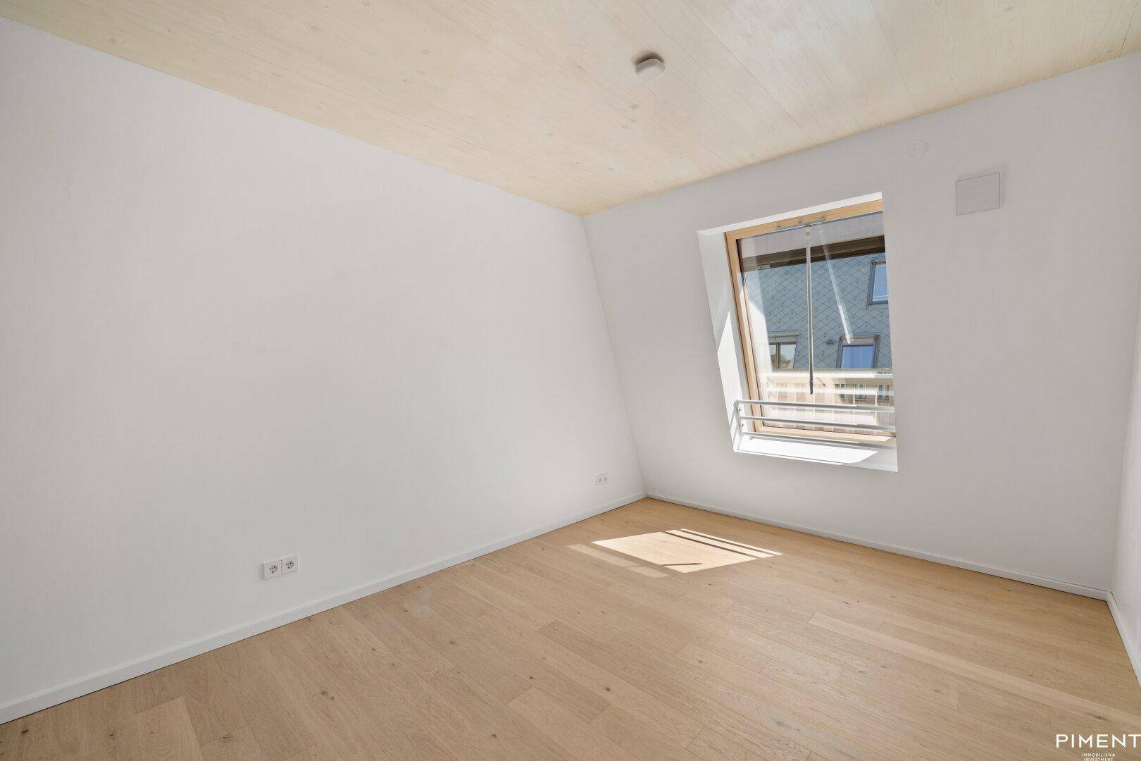 Geräumiges Zimmer mit Holzboden und Dachfenster, bietet viel natürliches Licht.