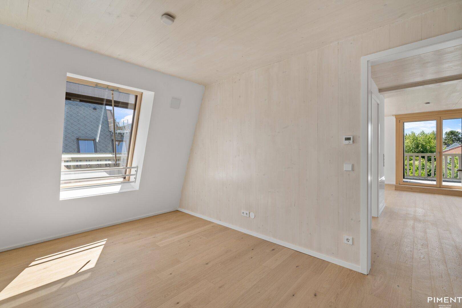 Helles Zimmer mit Holzboden und Dachfenster, ideal als Schlaf- oder Arbeitszimmer.