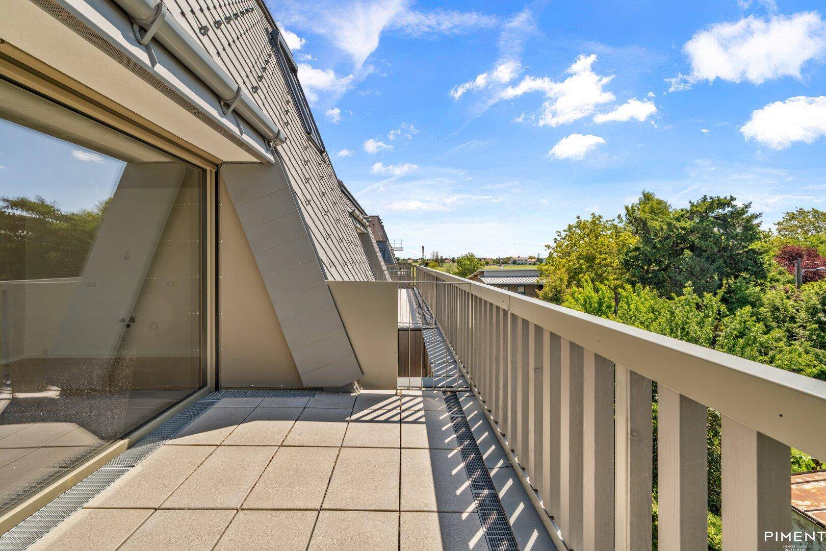 Geräumiger Balkon mit Fliesen und Blick auf die umliegende grüne Landschaft.