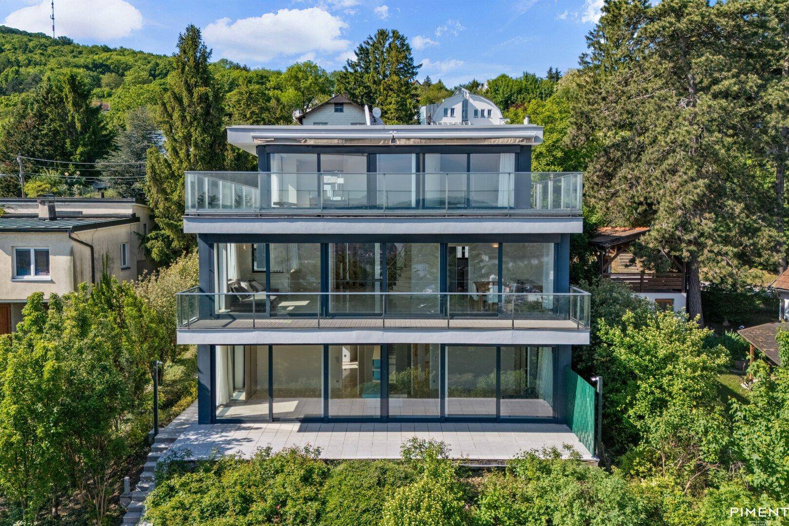 Zeitgenössische Architektur mit klaren Linien und großzügigen Fensterfronten, umgeben von üppigem Grün.