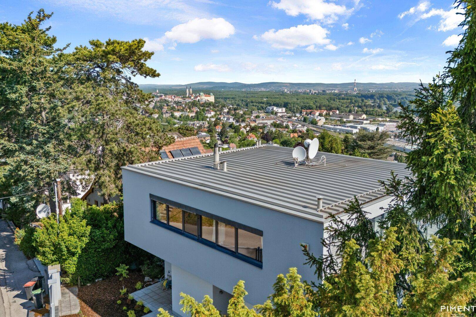 Dachansicht des modernen Gebäudes mit Flachdach und Satellitenschüsseln, umgeben von einer weiten Stadtlandschaft.