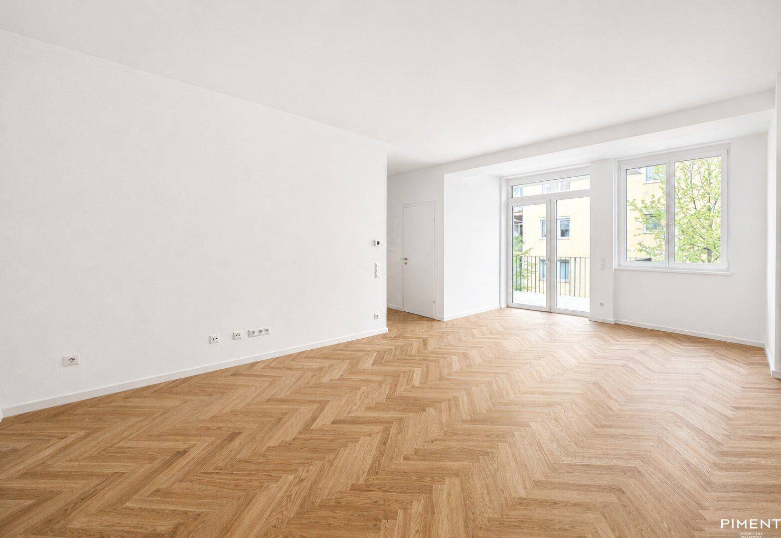 Geräumiges, helles Zimmer mit elegantem Fischgrätparkett und großen Fenstern.