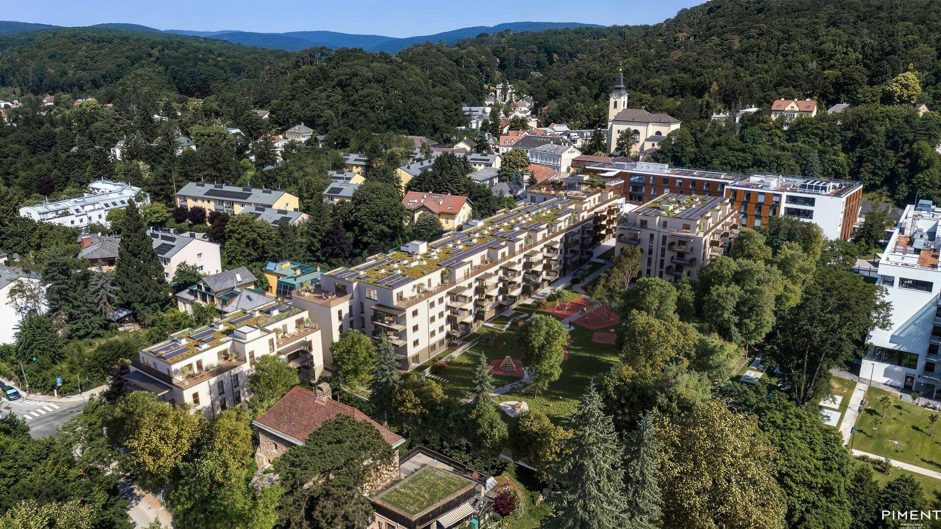 Luftaufnahme eines modernen Wohnkomplexes mit viel Grün und umliegenden Hügeln am Tag.