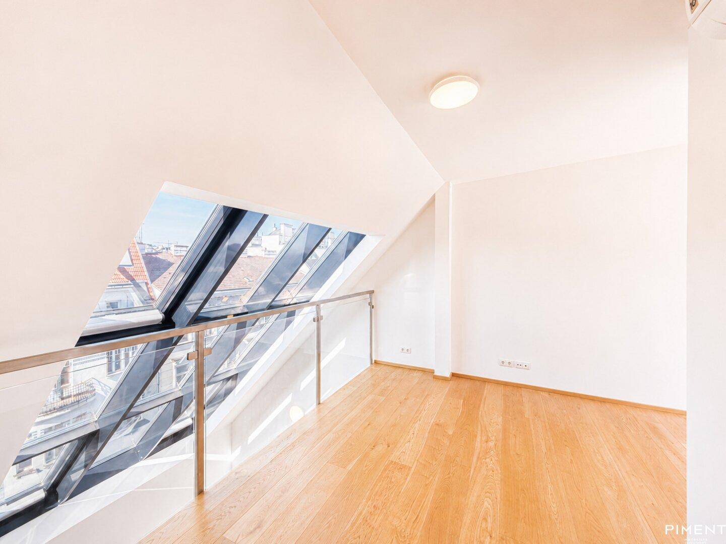 Obere Galerie mit Holzfußboden, Glasbrüstung und weitem Blick über die Dächer der Stadt.