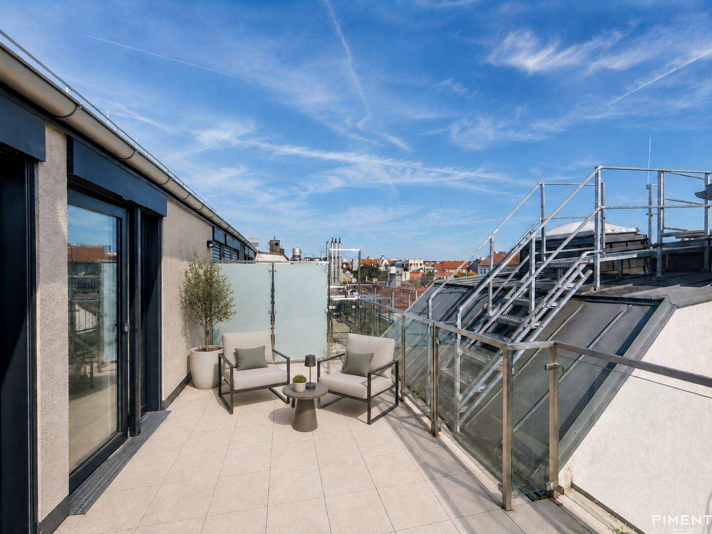 Sonnige Dachterrasse mit Stadtblick, Sitzgelegenheiten und Glasgeländer.