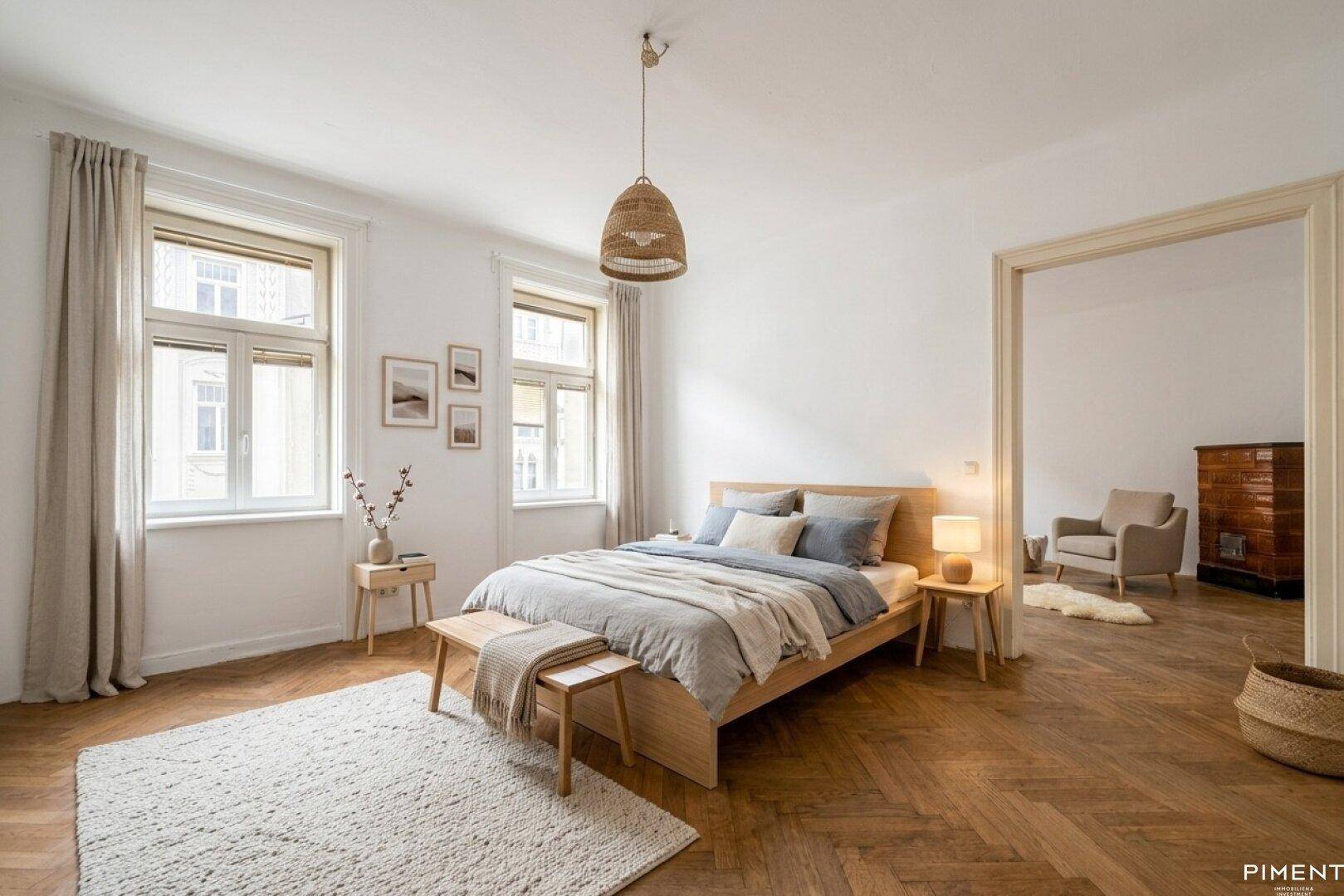 Helles Schlafzimmer mit Holzbett, Fischgrätparkett und Zugang zu einem weiteren Raum.