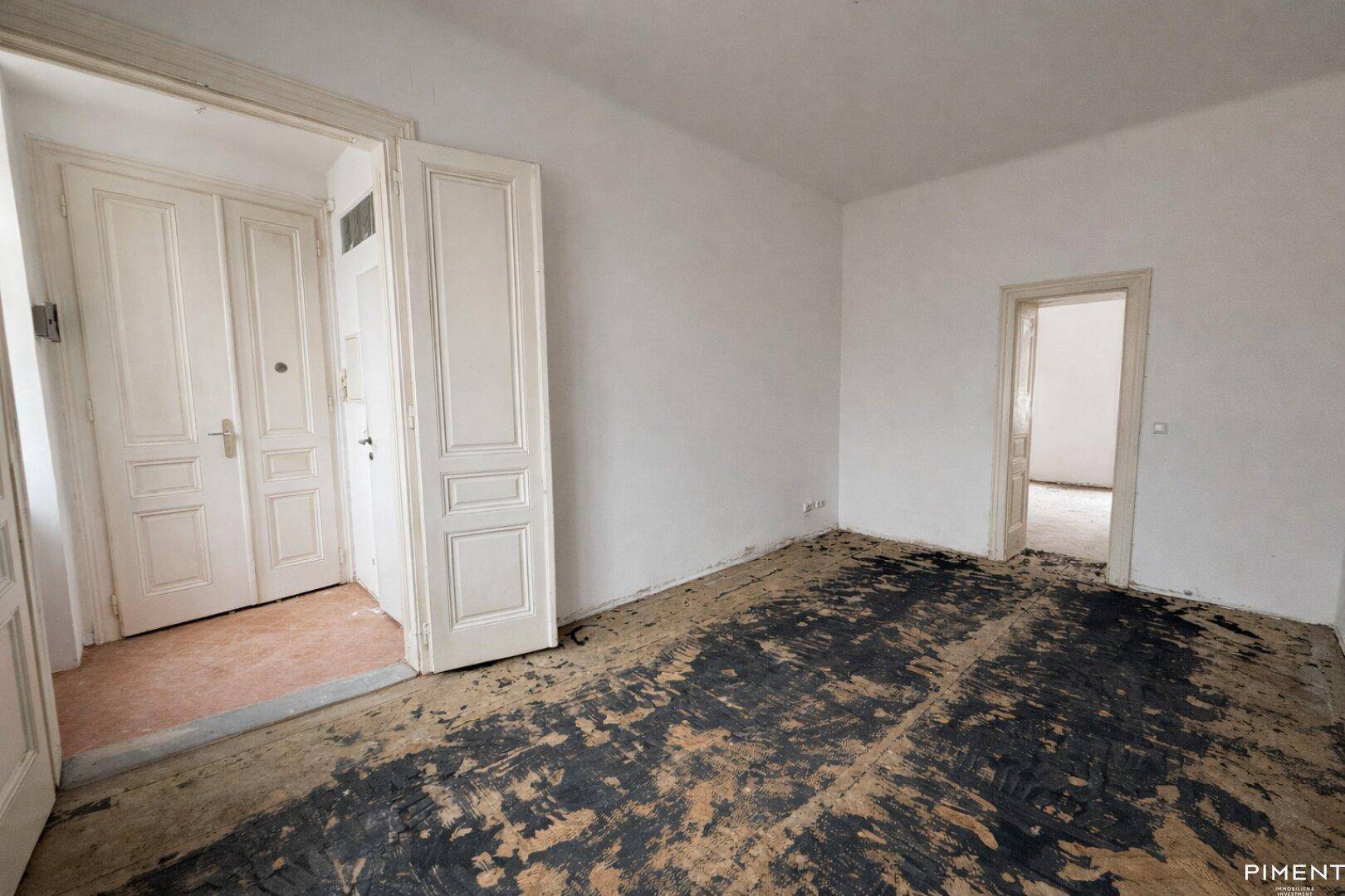Leerer Flur mit freigelegten Dielen und zwei Türen, bereit für die Renovierung.