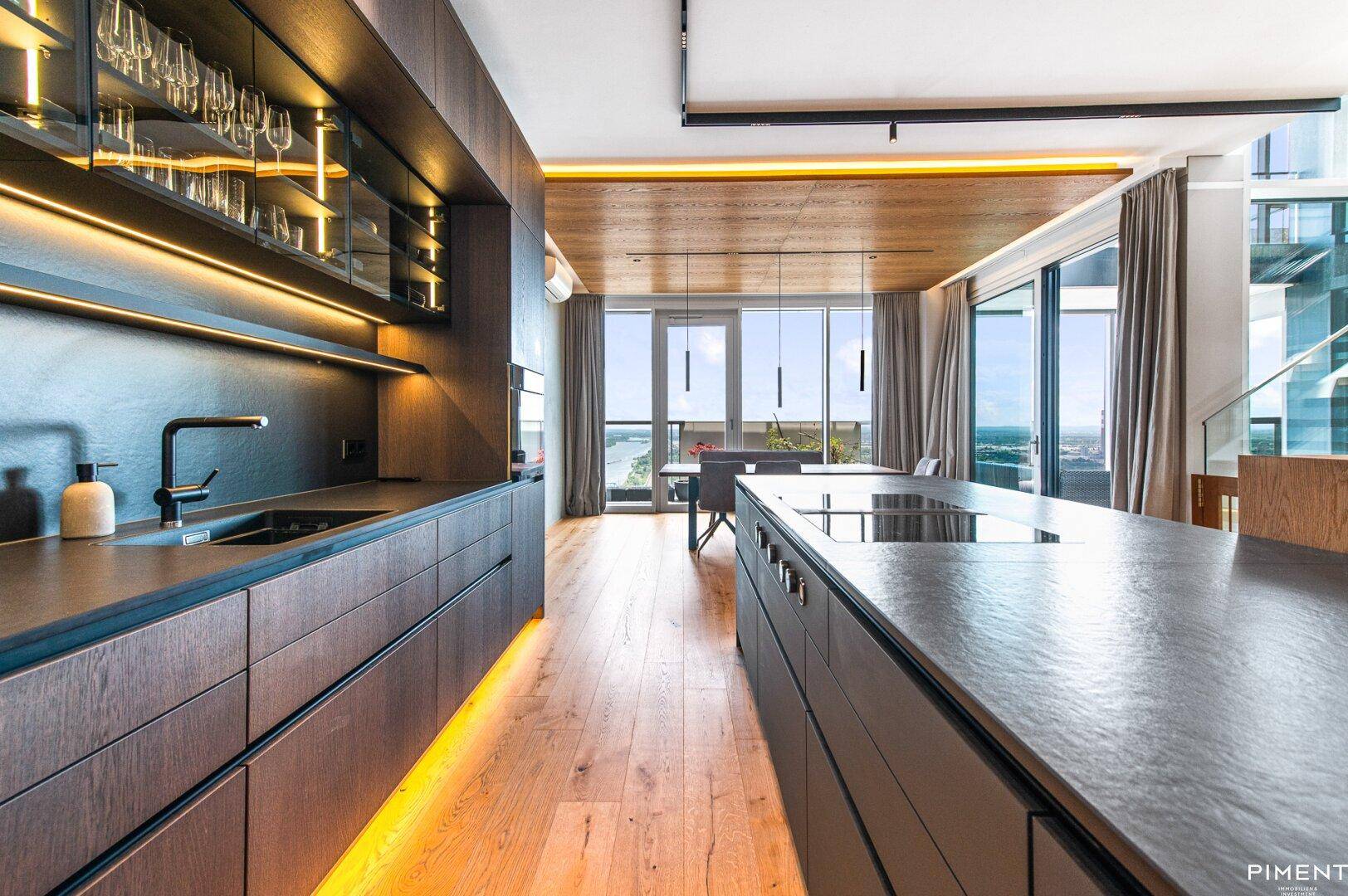 Elegante Küche mit dunklen Holzfronten, integrierten Geräten und Blick auf den Essbereich und die Stadt.