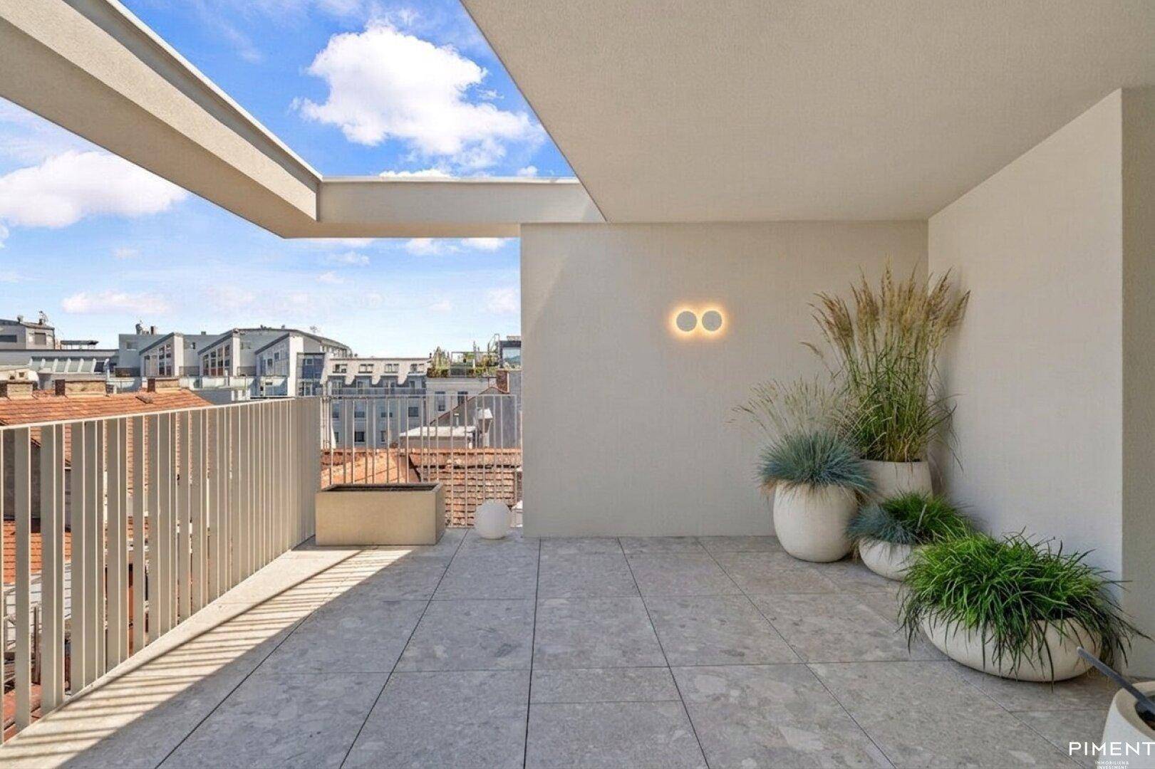 Helle Terrasse mit modernen Pflanzgefäßen und weitem Blick über die Dächer der Stadt.