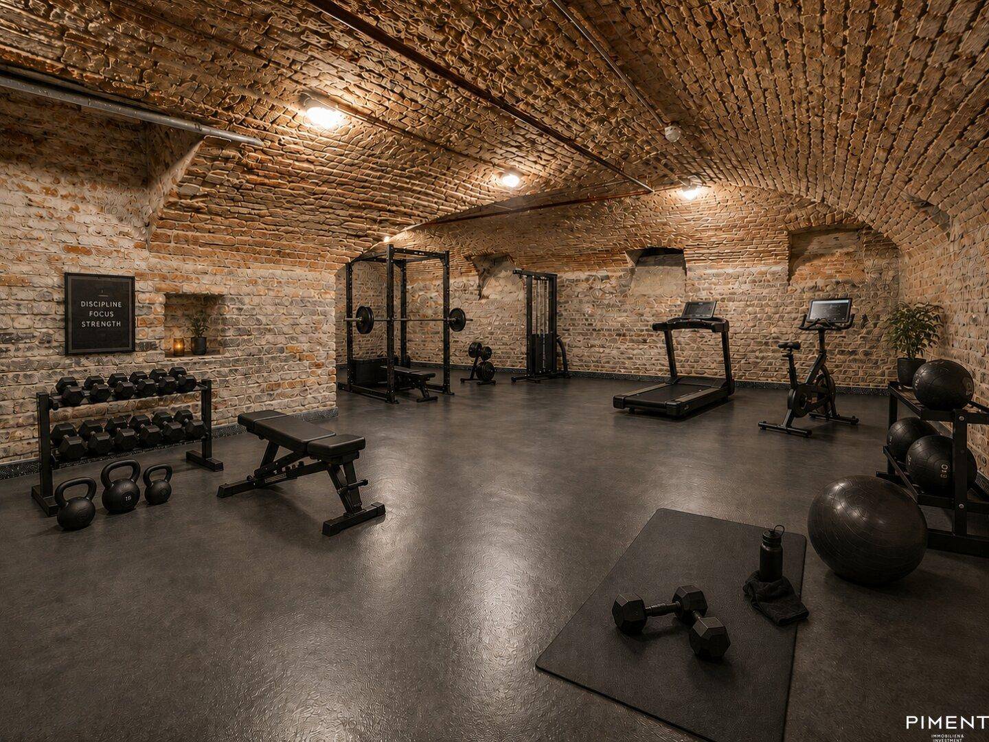 Gut ausgestatteter Fitnessraum im Keller mit Gewölbedecke und Ziegelwänden.